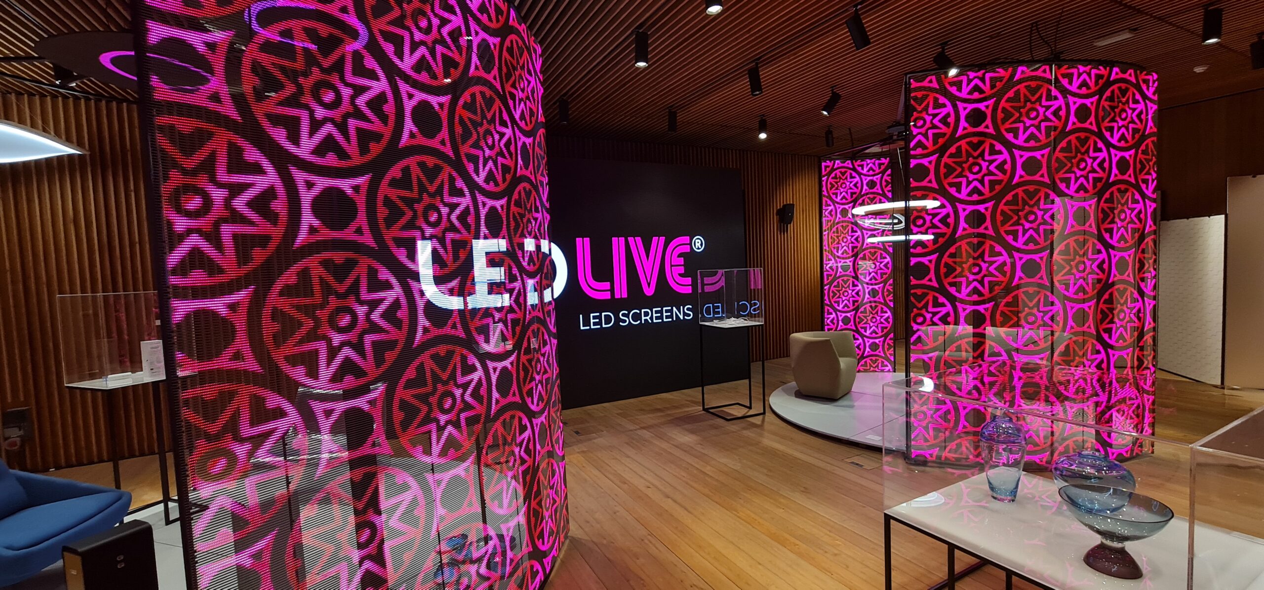 Różowe mozaikowe wzory na transparentnych ekranach  LED , w tle logo LedLIVE w czasie EXPO Dubai 2020