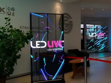 Transparent led advertising board standing next to green plant in lobby