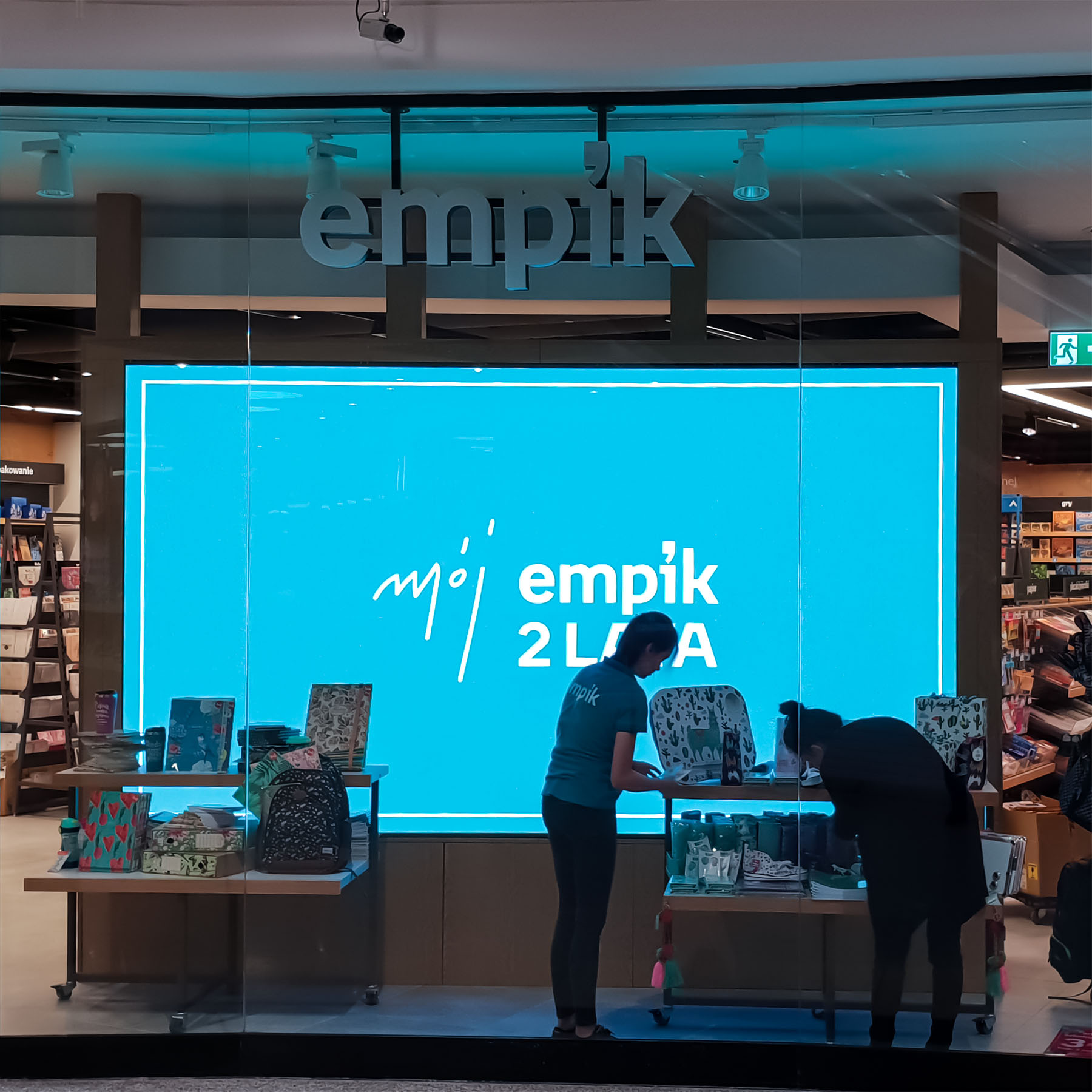 Wewnętrzny ekran LED znajdujący się za przeszkloną witryną sklepu Empik w Krakowie