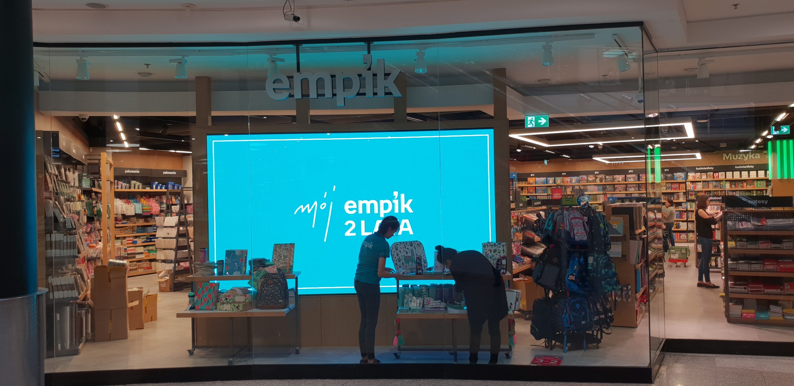 Wewnętrzny ekran LED znajdujący się za przeszkloną witryną sklepu Empik w Krakowie