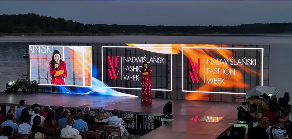 Joanna Horodyńska prowadząca Nadwiślański Fashion Week na tle transparentnych ekranów LED