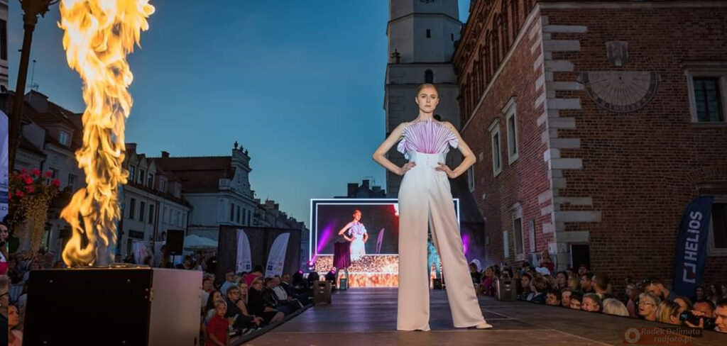 Modelka na tle ekranu LED przy słupie ognia w trakcie Nadiwślański Fashion Week