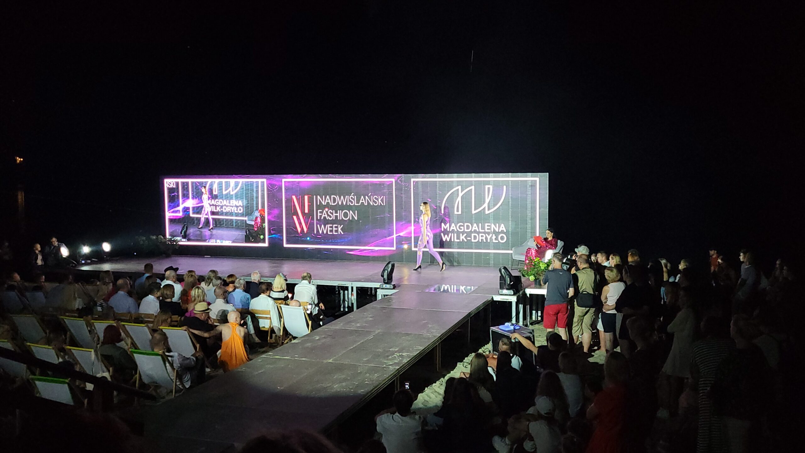 Modelka w trakcie pokazu na scenie z transparentych ekranów LED w trakcie Nadwiślańskiego Fashion Week 2022